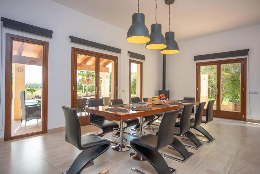 Comedor con una mesa larga y lámparas colgantes oscuras.