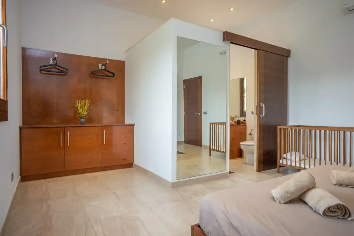Dormitorio con un armario de madera, un mueble bajo y una cama.