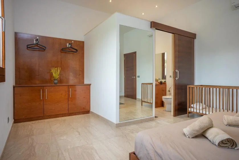 Un dormitorio con cama, armario de madera y una entrada abierta al baño.