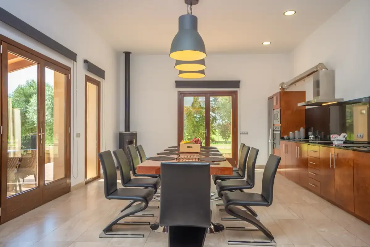 Un comedor con una mesa larga y sillas junto a una cocina.