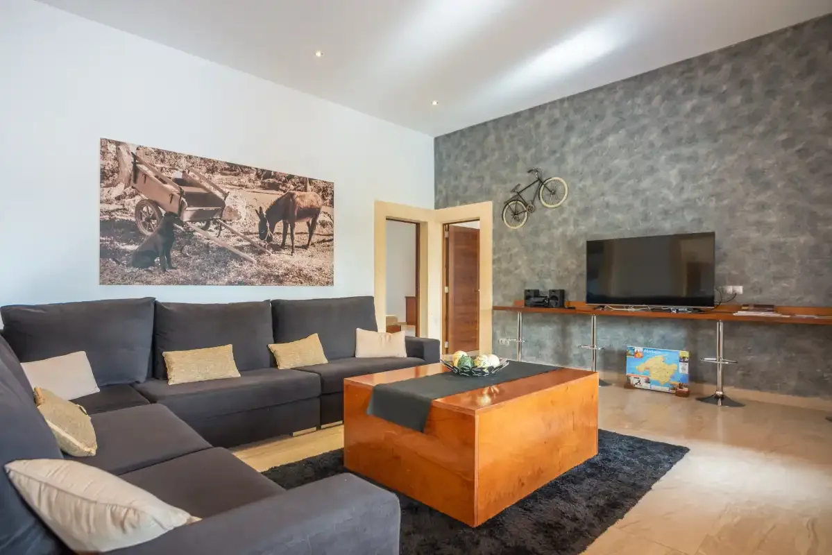 Una sala de estar moderna con asientos seccionales, una mesa de centro de madera y un televisor.