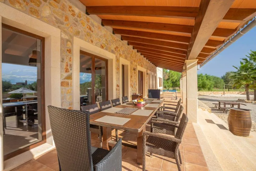 Comedor exterior cubierto con una mesa larga junto a una pared de piedra.