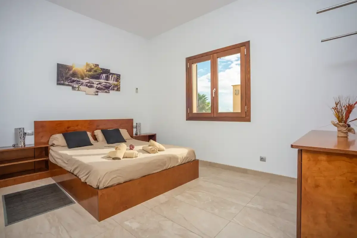 Un dormitorio con una cama doble y una ventana con vistas a la vegetación.