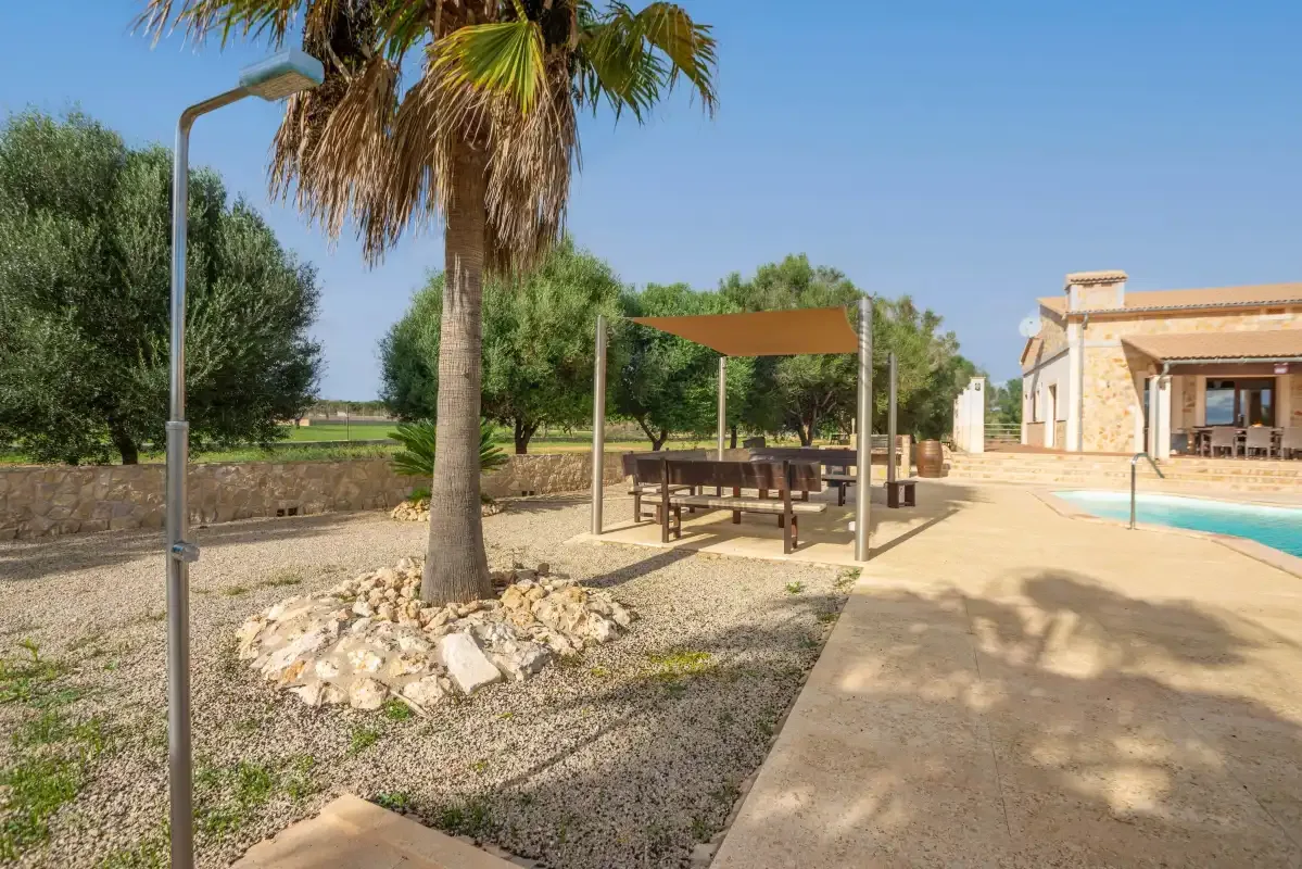 Una zona de piscina al aire libre con un pabellón de sombra junto al agua.