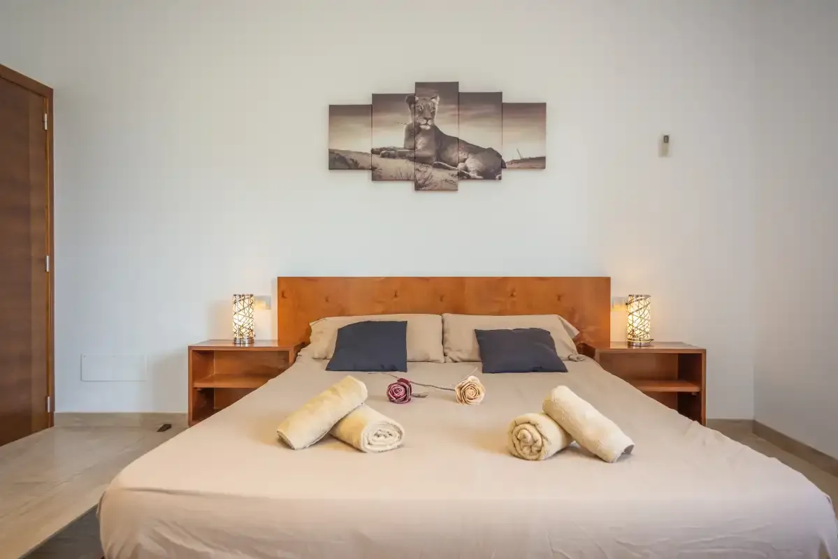 Dormitorio con cama doble, mesitas de noche y un cuadro en la pared.