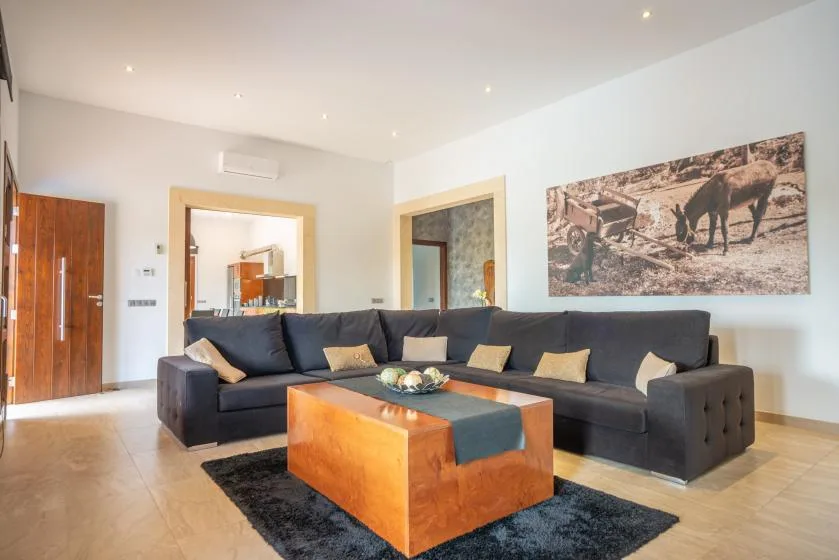 Una sala luminosa con un sofá seccional oscuro y una mesa de centro de madera.