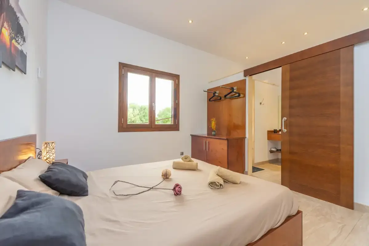 Un dormitorio con cama, armario de madera y ventana.