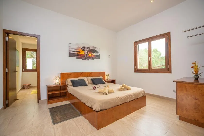 Un dormitorio con una cama, mesitas de noche y una ventana.