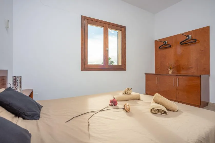Un dormitorio con una cama, una ventana con marco de madera y un armario.
