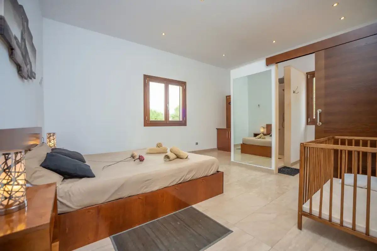 Un dormitorio con una cama, una ventana y una puerta abierta al baño.