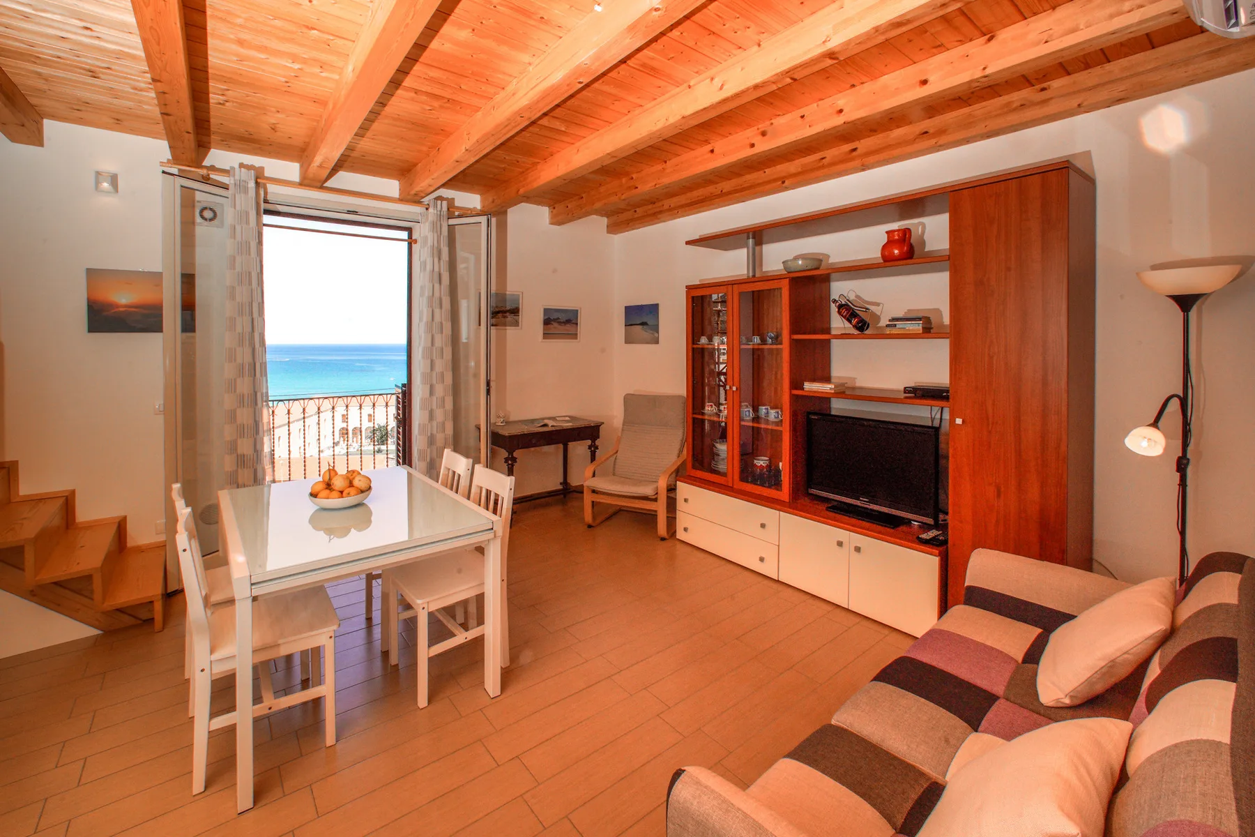 A living and dining area with a table, seating, and a wooden entertainment unit.