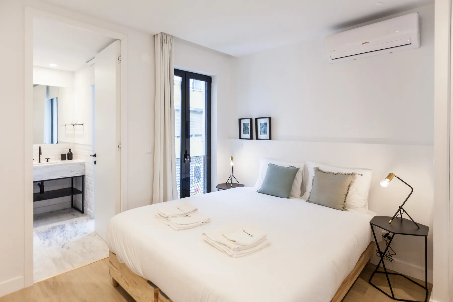 Un dormitorio luminoso con una cama bien hecha y una ventana al lado.