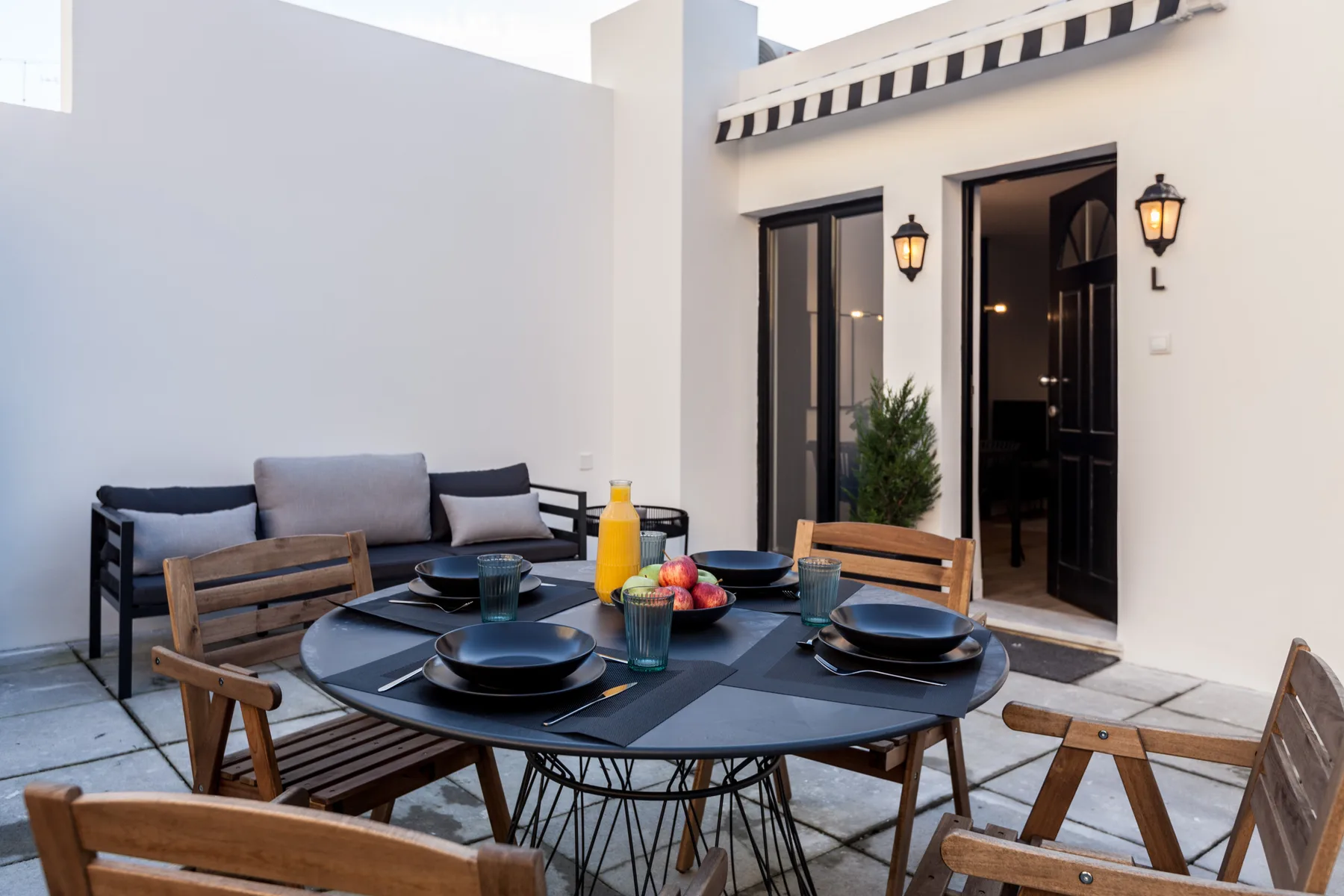 Un comedor en el patio con la mesa puesta y asientos al aire libre.