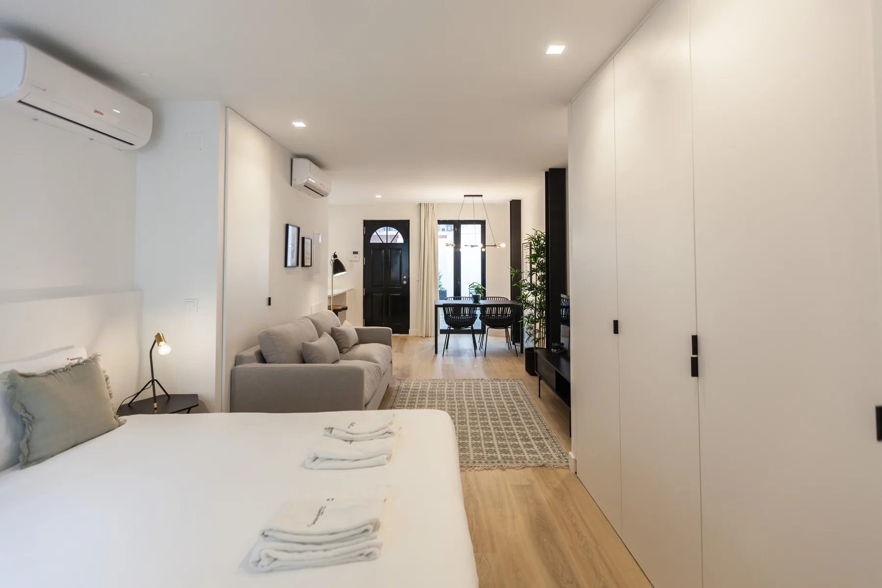 Una luminosa zona de estudio para dormir y estar, con cama, asientos y mesa de comedor.