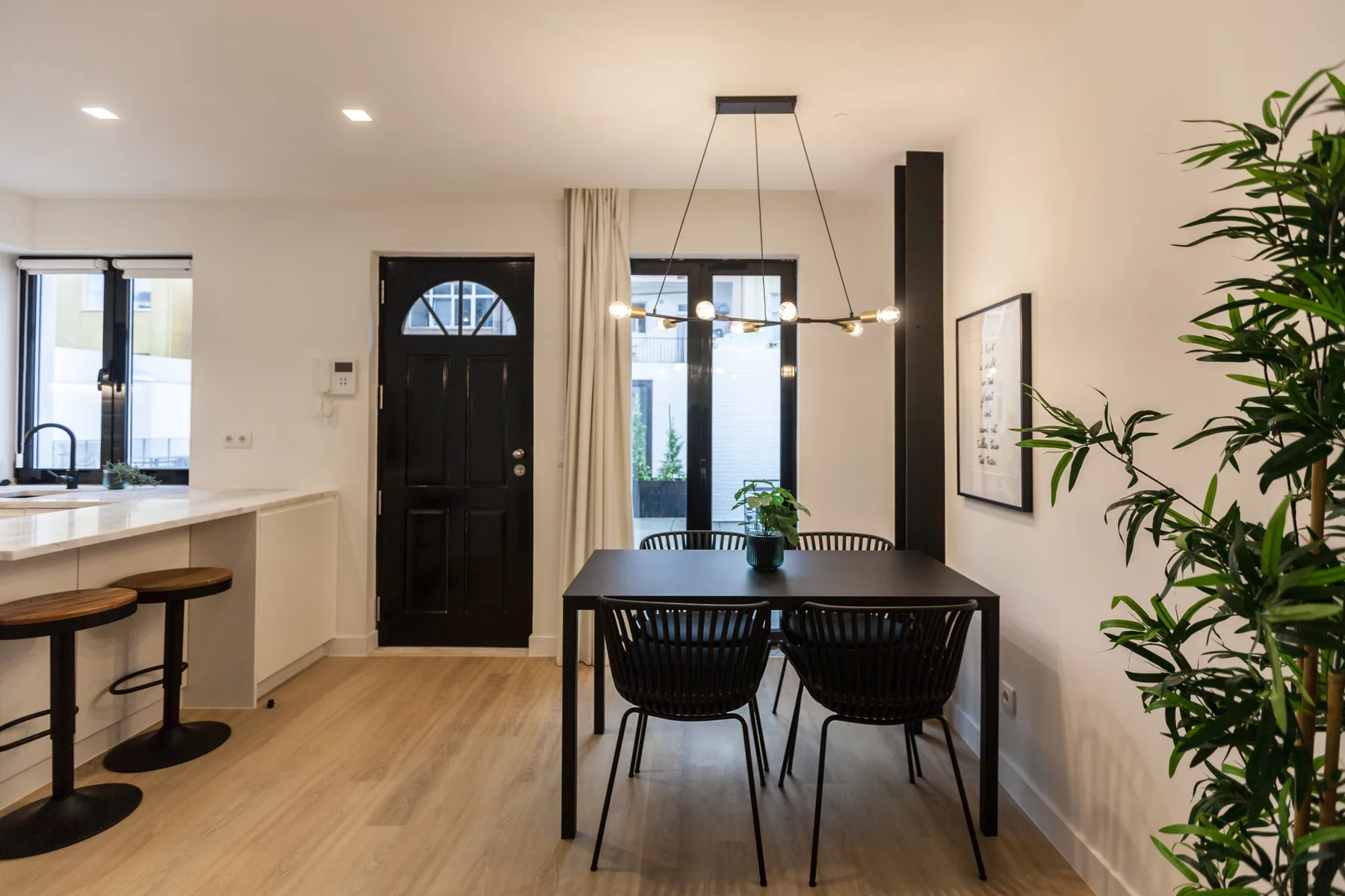 Comedor con una mesa oscura y sillas junto a una encimera de cocina.