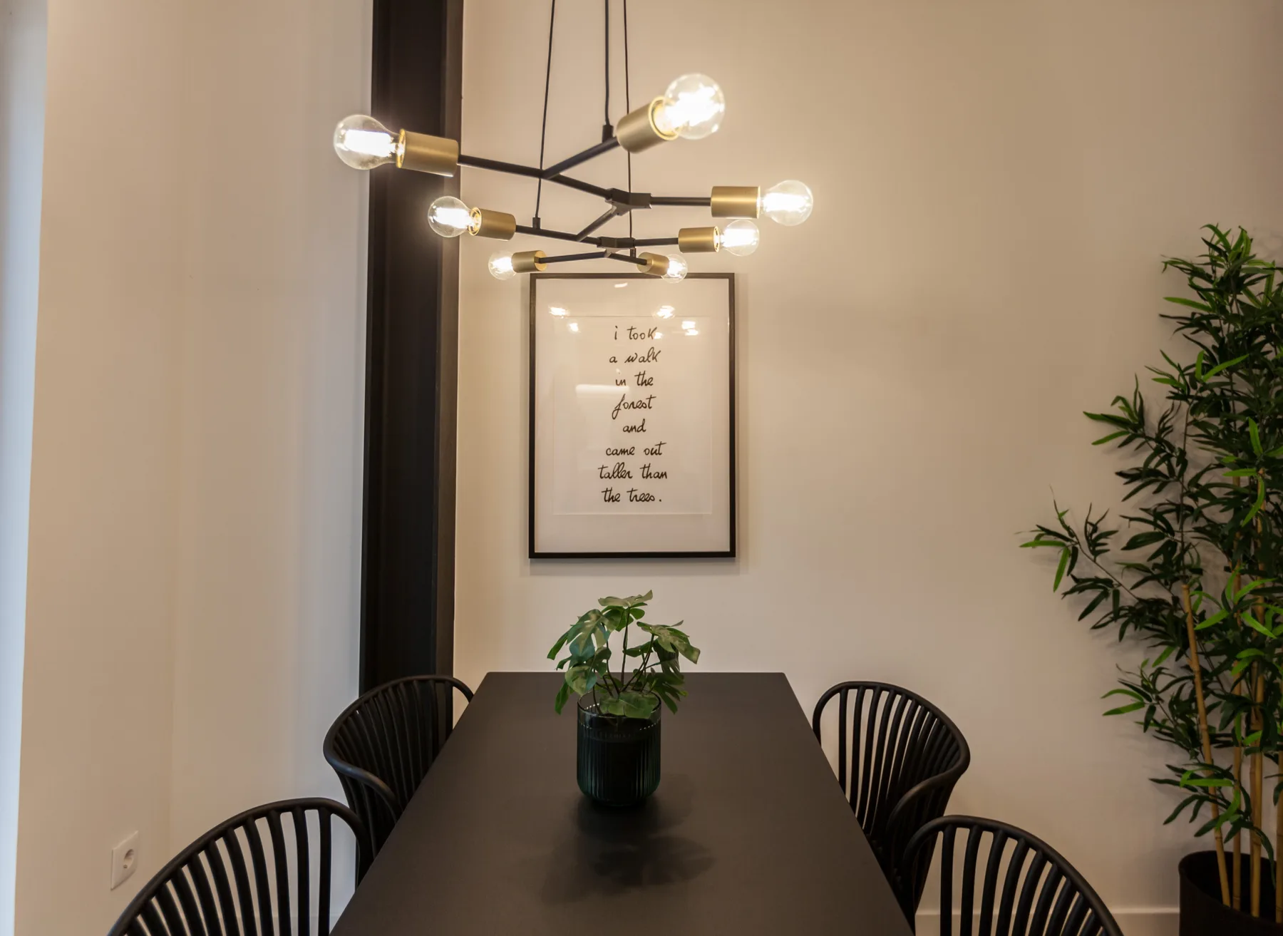Un comedor con una mesa oscura, sillas y una lámpara colgante.