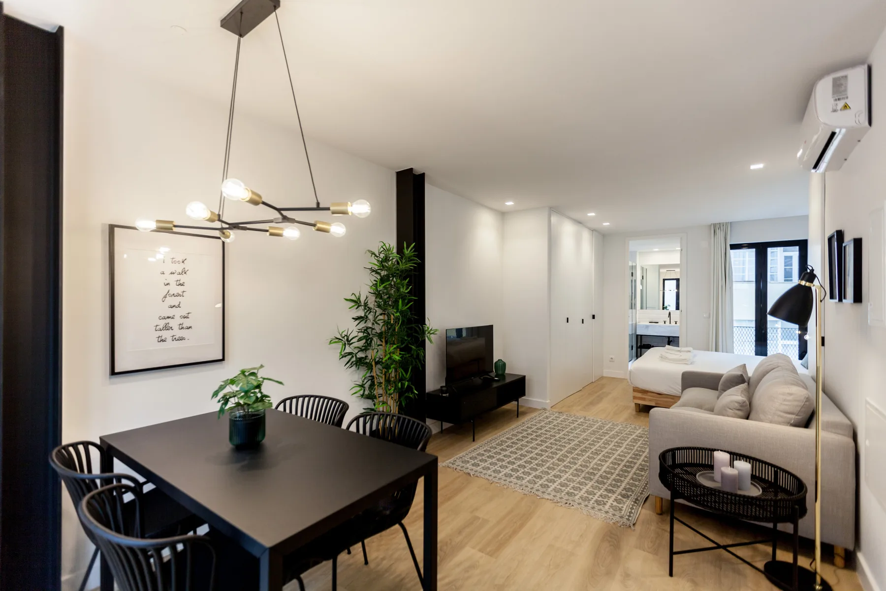 A bright studio living area combines dining and seating spaces with a rug.