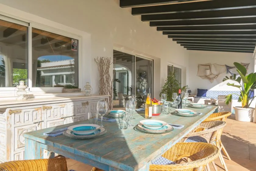 Un comedor luminoso tiene una mesa larga puesta con platos y cristalería.