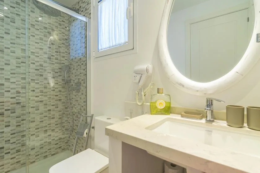 Un baño luminoso con ducha de vidrio, inodoro y lavabo.