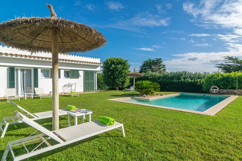 Un patio soleado con asientos de descanso junto a una piscina.