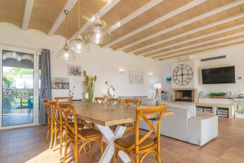 Un comedor y sala de estar de concepto abierto tiene una mesa de madera y asientos frente a un televisor.