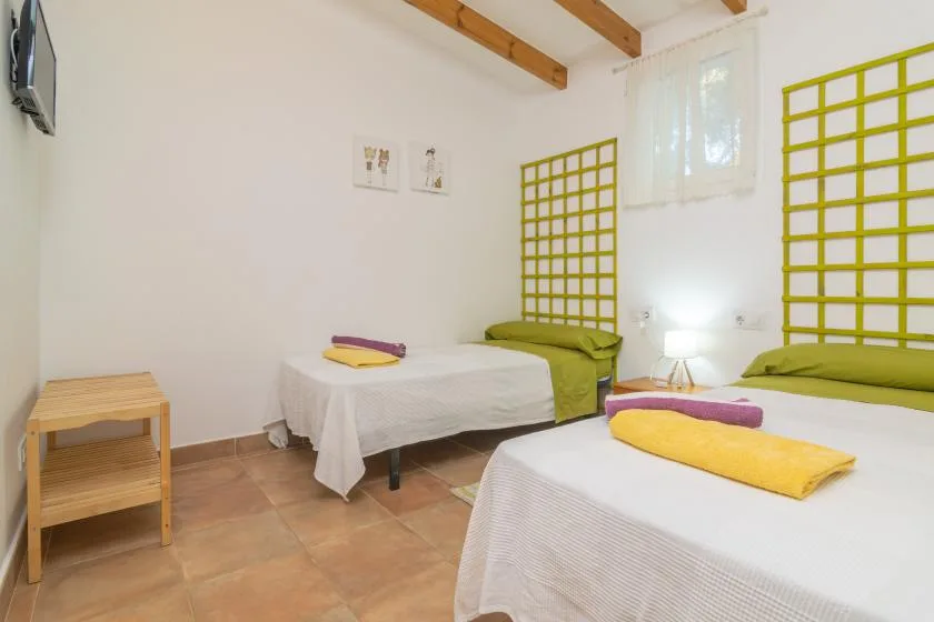 Un dormitorio luminoso con dos camas y detalles amarillos.