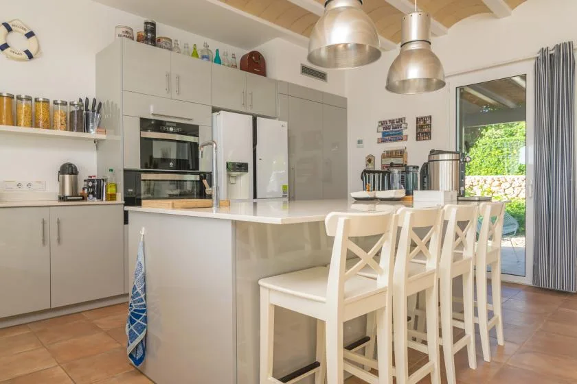 Una cocina luminosa con una isla central y asientos de barra.