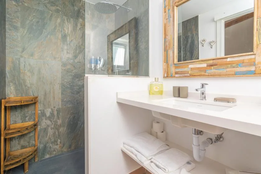 Un lavabo de baño con espejo junto a una ducha de vidrio.