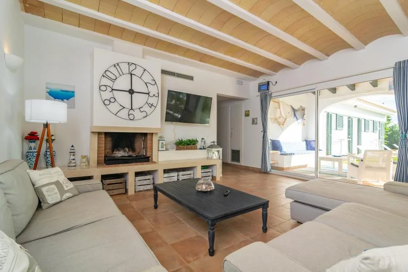 Una luminosa sala de estar con asientos seccionales, chimenea y puertas corredizas de vidrio.
