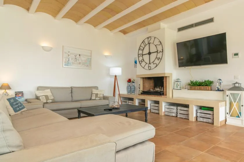 Una sala de estar con asientos seccionales, una mesa de centro y un televisor en la pared.