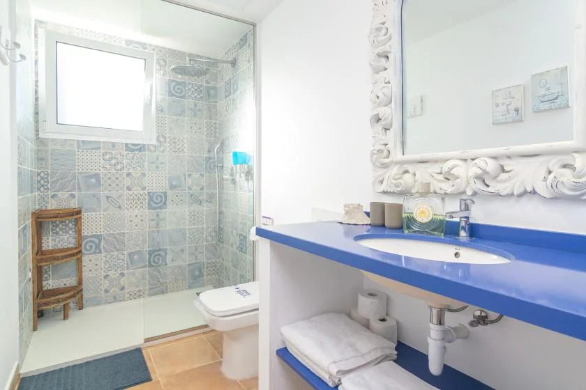 Un baño con una zona de ducha con azulejos y un lavabo con encimera azul.