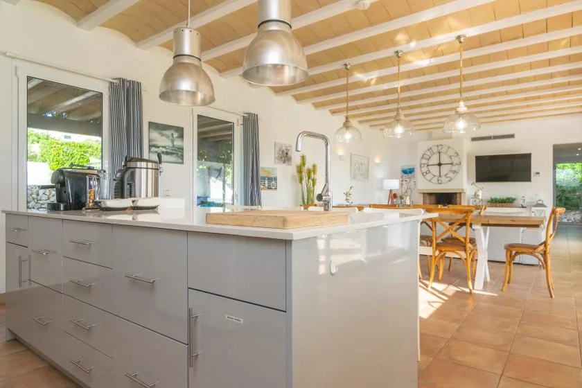 Una cocina abierta y luminosa con una gran isla y vigas de madera en el techo.
