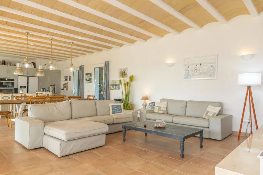 Una sala de estar con asientos seccionales, una mesa de centro y una cocina abierta.