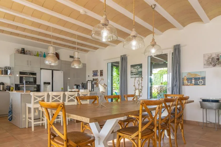 Un comedor con una larga mesa de madera y asientos bajo lámparas colgantes.