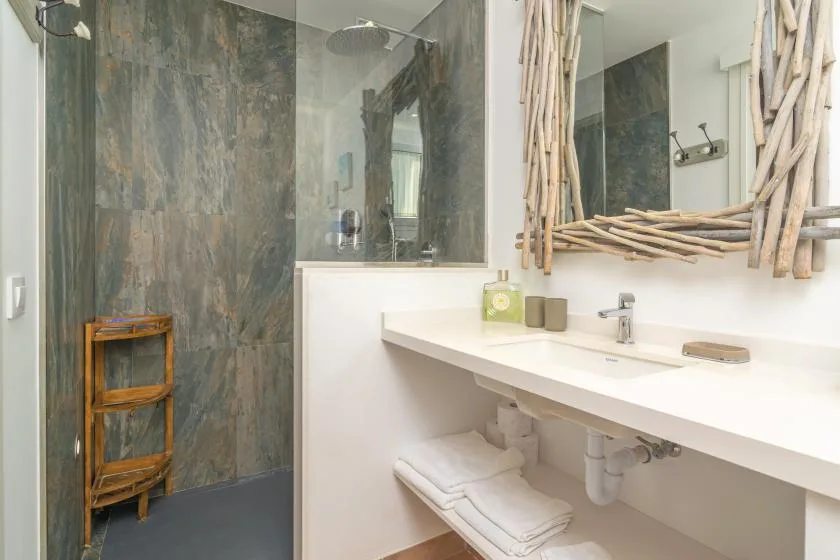 Un baño con ducha, una encimera larga con lavabo y un espejo enmarcado.