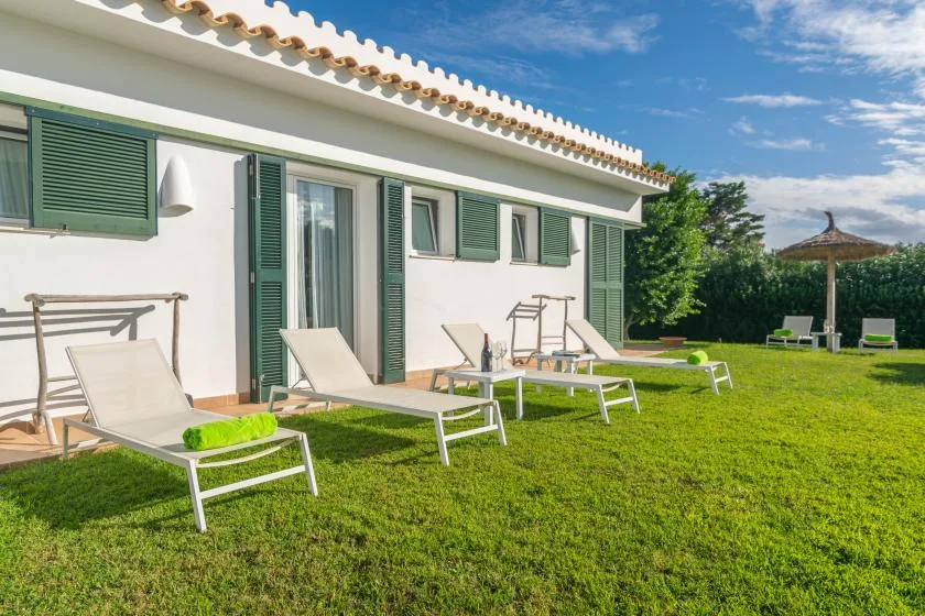 Un edificio blanco da a un césped con asientos al aire libre.