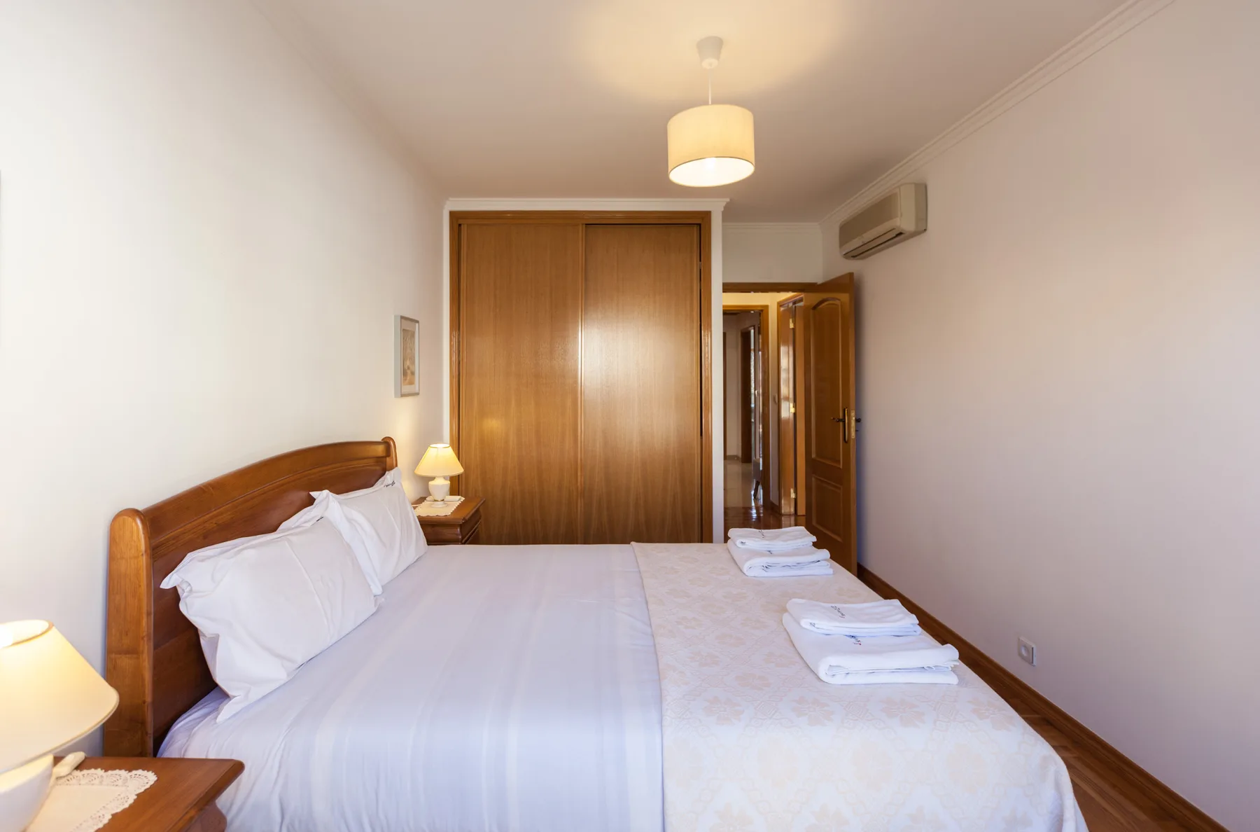 Dormitorio con una cama bien hecha y un armario de madera.