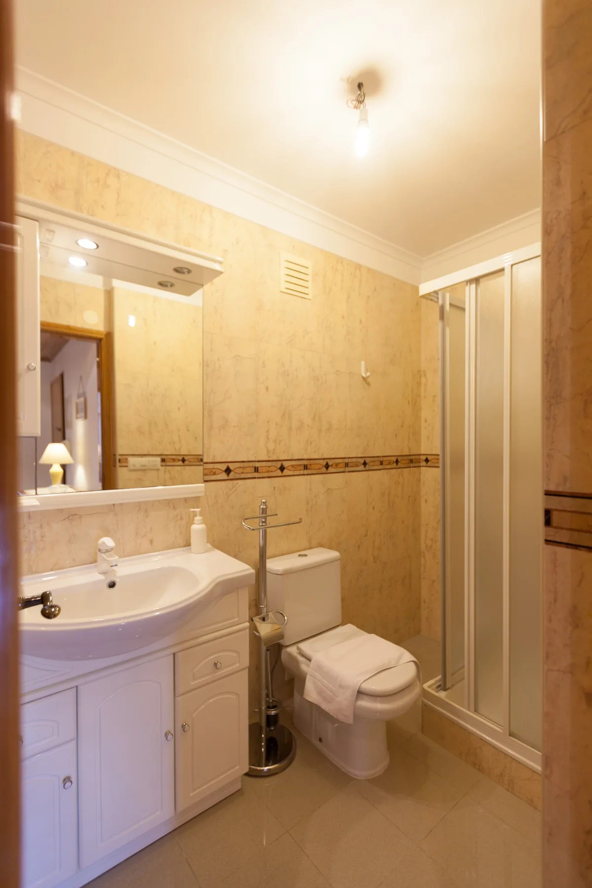 Un baño con lavabo, inodoro y ducha con mampara de vidrio.