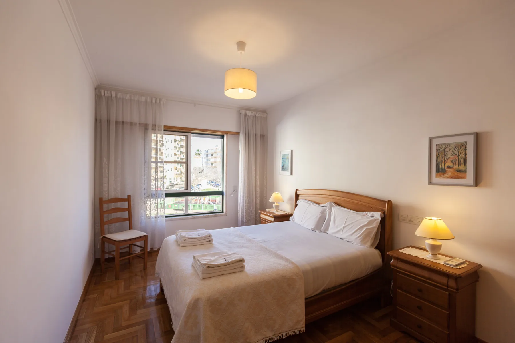 Dormitorio con una cama de madera, mesillas de noche y una ventana con cortinas.