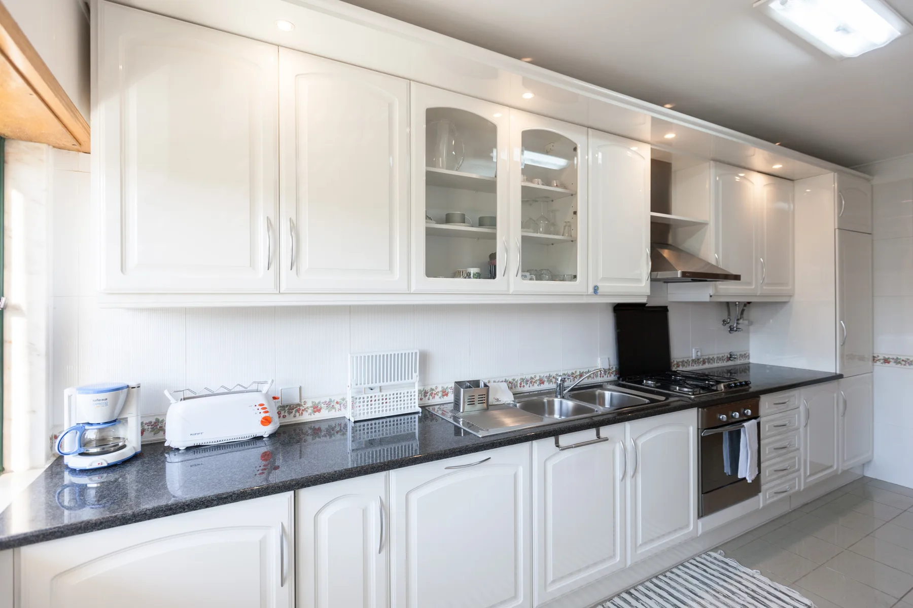 Una cocina luminosa con armarios blancos y una encimera oscura.
