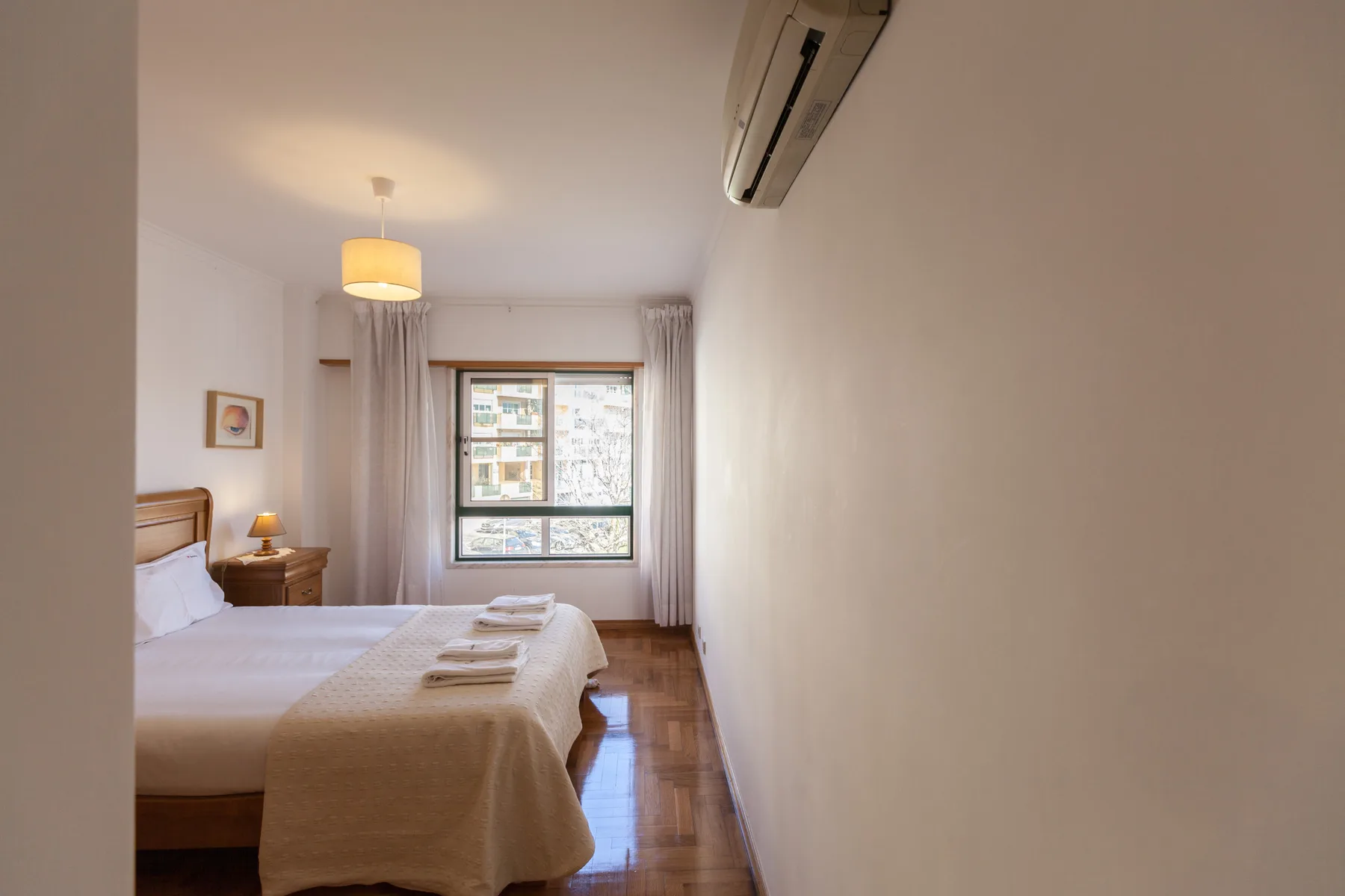 Dormitorio con una cama junto a una ventana y cortinas.