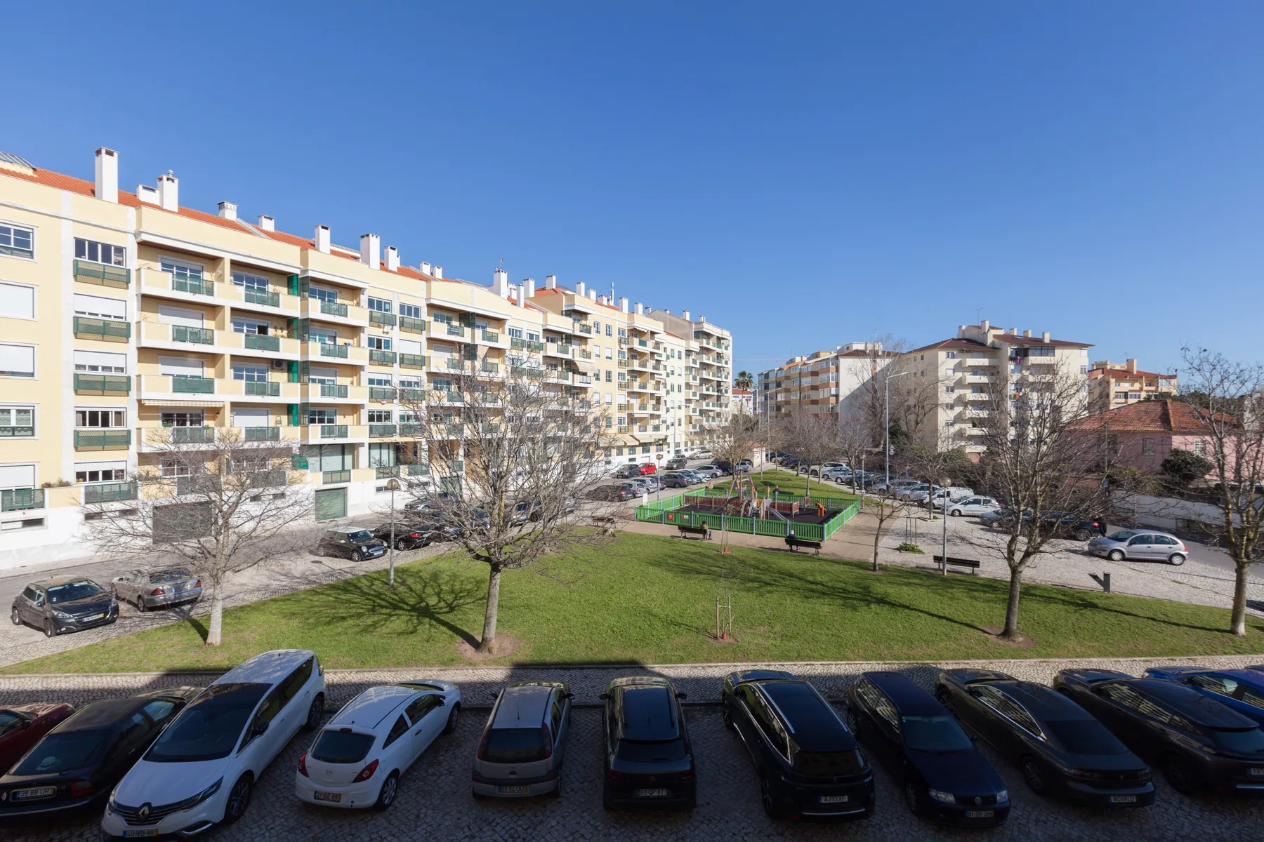 Edificios residenciales dan a un patio con césped y una zona de estacionamiento.