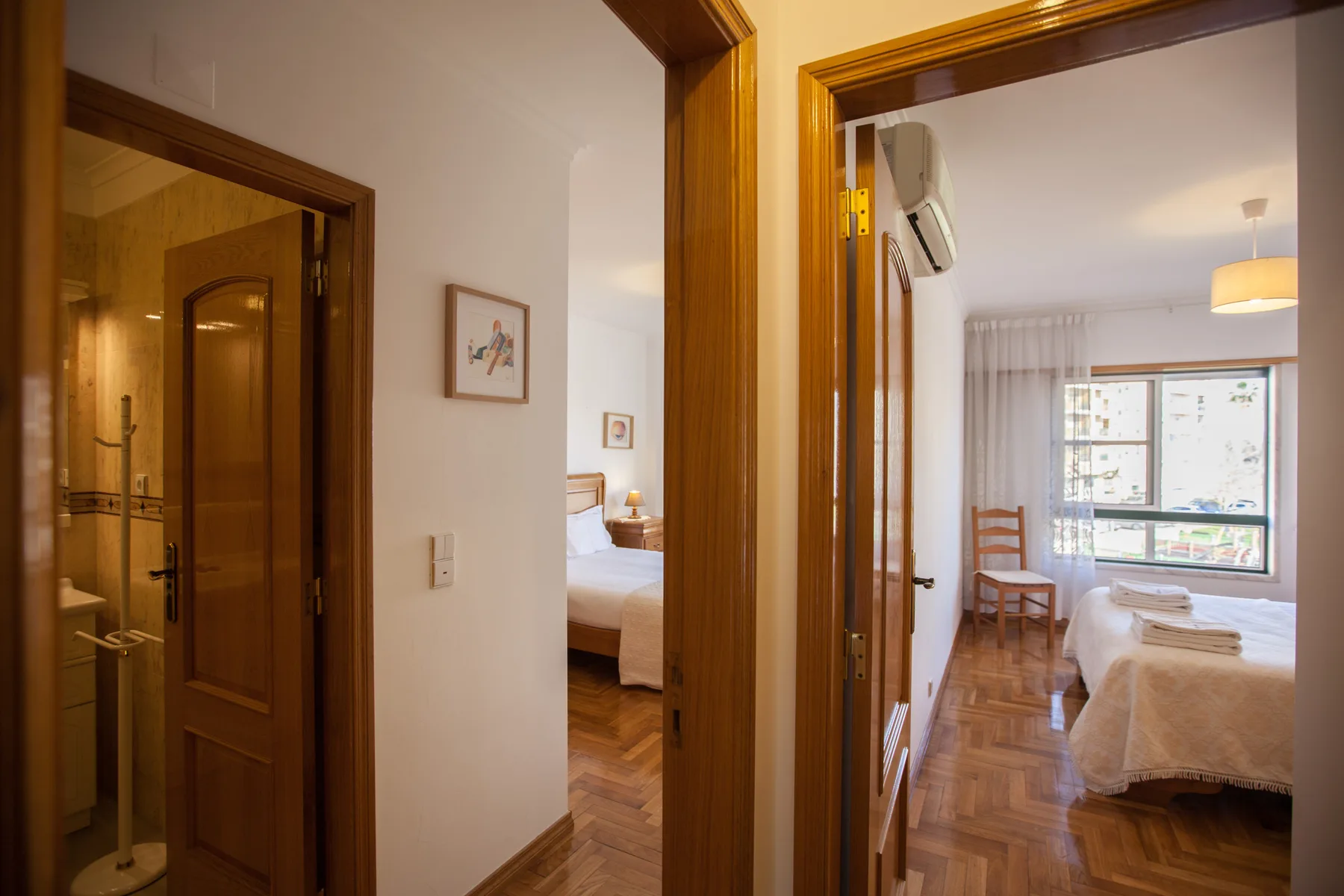 Se ve un dormitorio con una cama y una silla a través de una puerta abierta.