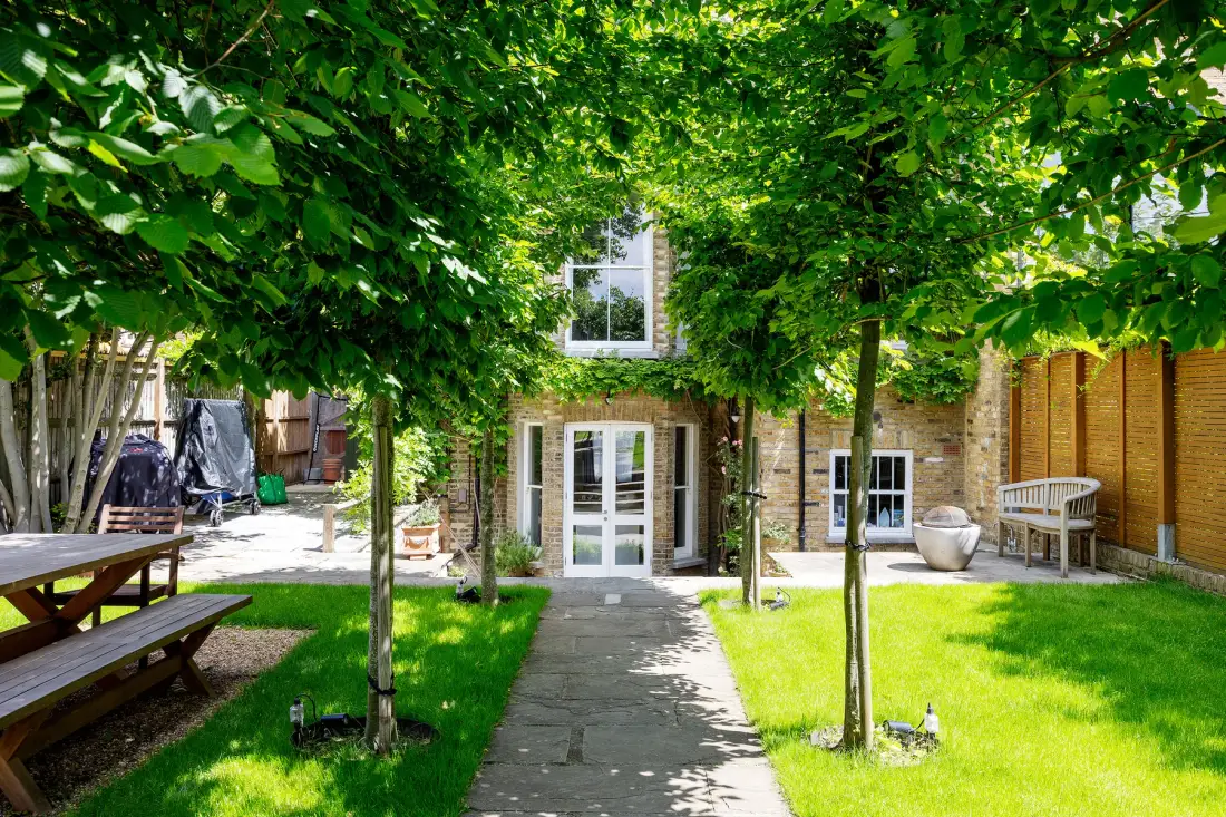 A leafy courtyard with a stone path leading to a building entrance.