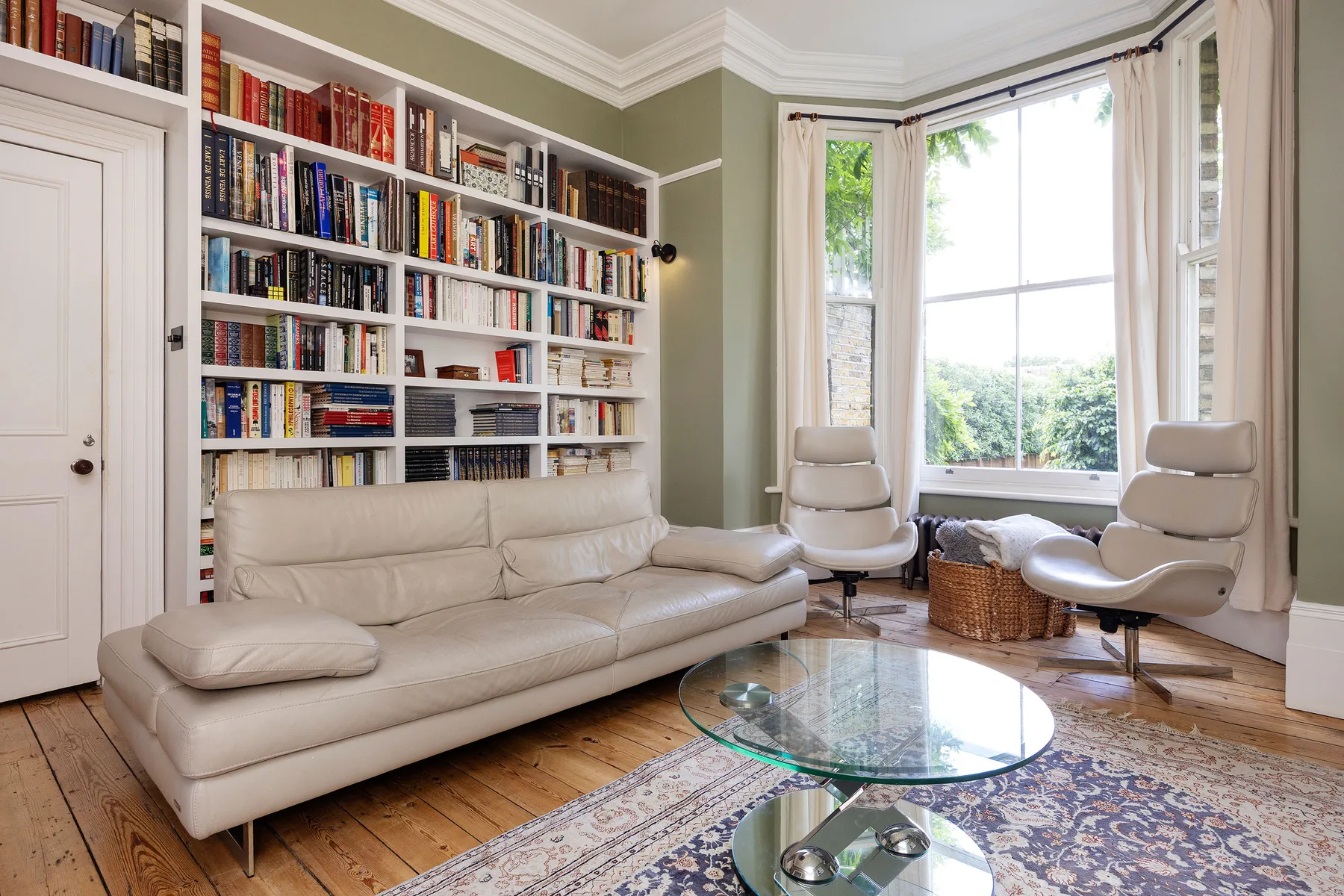 Una sala luminosa con estanterías empotradas y asientos junto a una ventana grande.