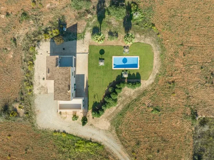 Vista aérea de una propiedad ajardinada con una piscina pequeña junto a un edificio.
