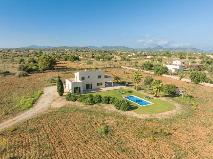 Una casa moderna y una piscina se encuentran en un campo abierto y seco.