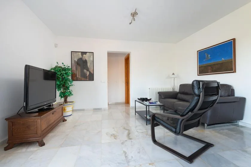 Una sala de estar con asientos, un televisor y una mesa de centro.