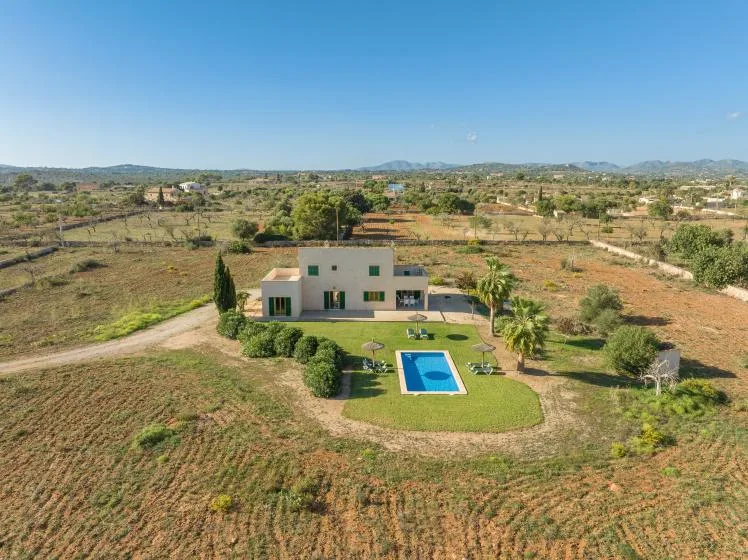 Vista aérea de una casa con césped y piscina en un paisaje rural seco.