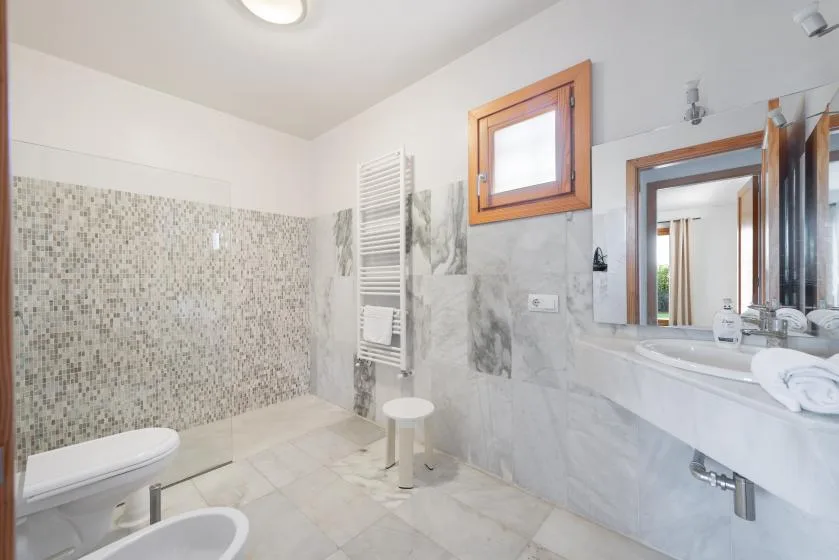 Un baño luminoso con inodoro, zona de ducha y lavabo.